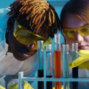 Two scientists work with test tubes in a laboratory, analyzing chemical reactions.